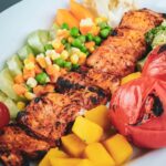 Healthy Homemade Grilled chicken with colorful roasted veggies served in a white ceramic plate.