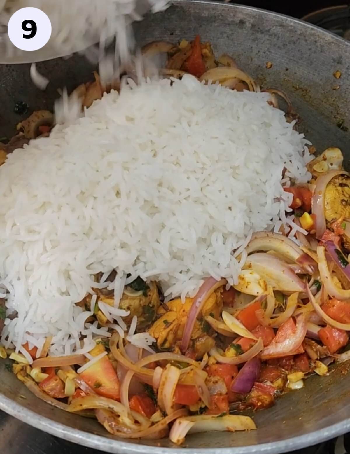 Partially cooked rice added to a large pan/kadhai.