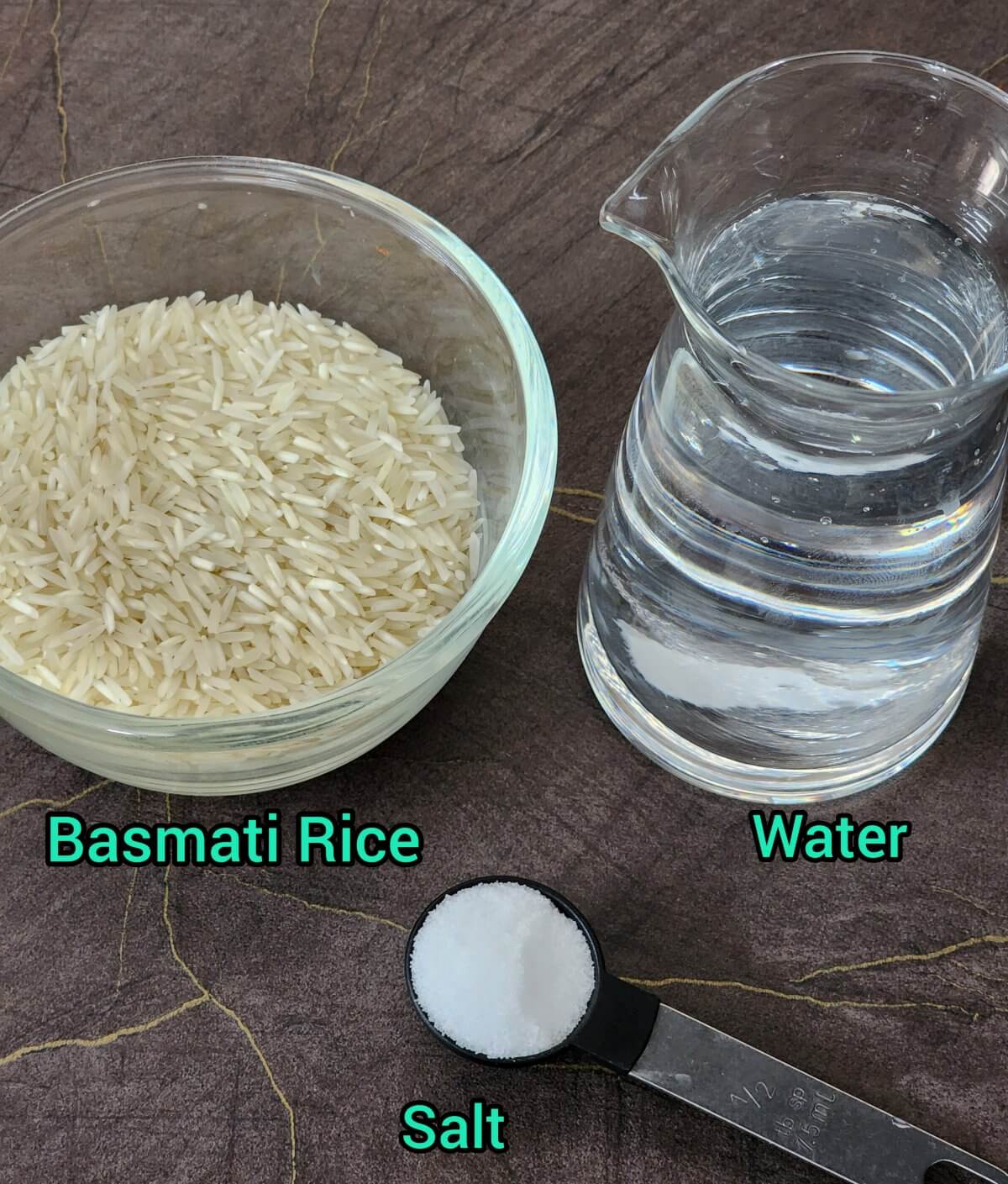 Rice in a glass bowl, water in glass jug, and salt in a spoon measure.