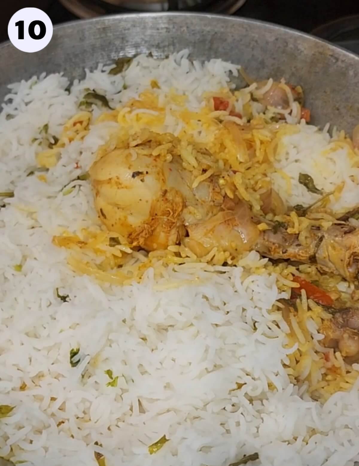 Cooked chicken drumstick place on top of cooked biryani.